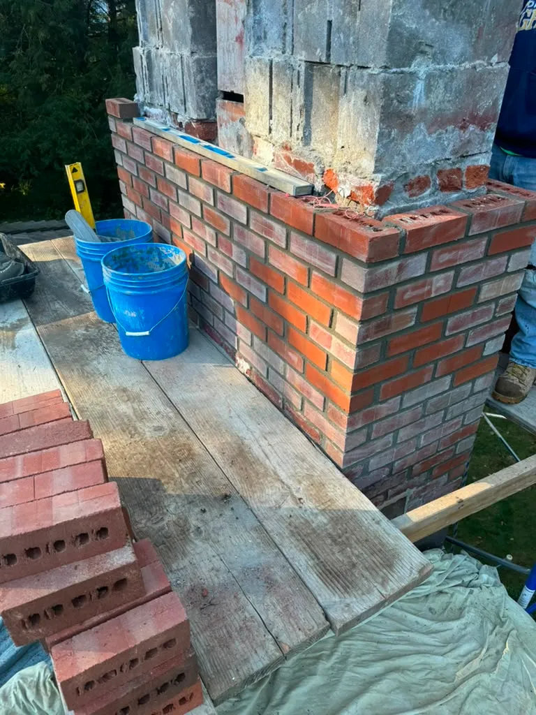 Mason removing damaged masonry before rebuilding a structure in Connecticut