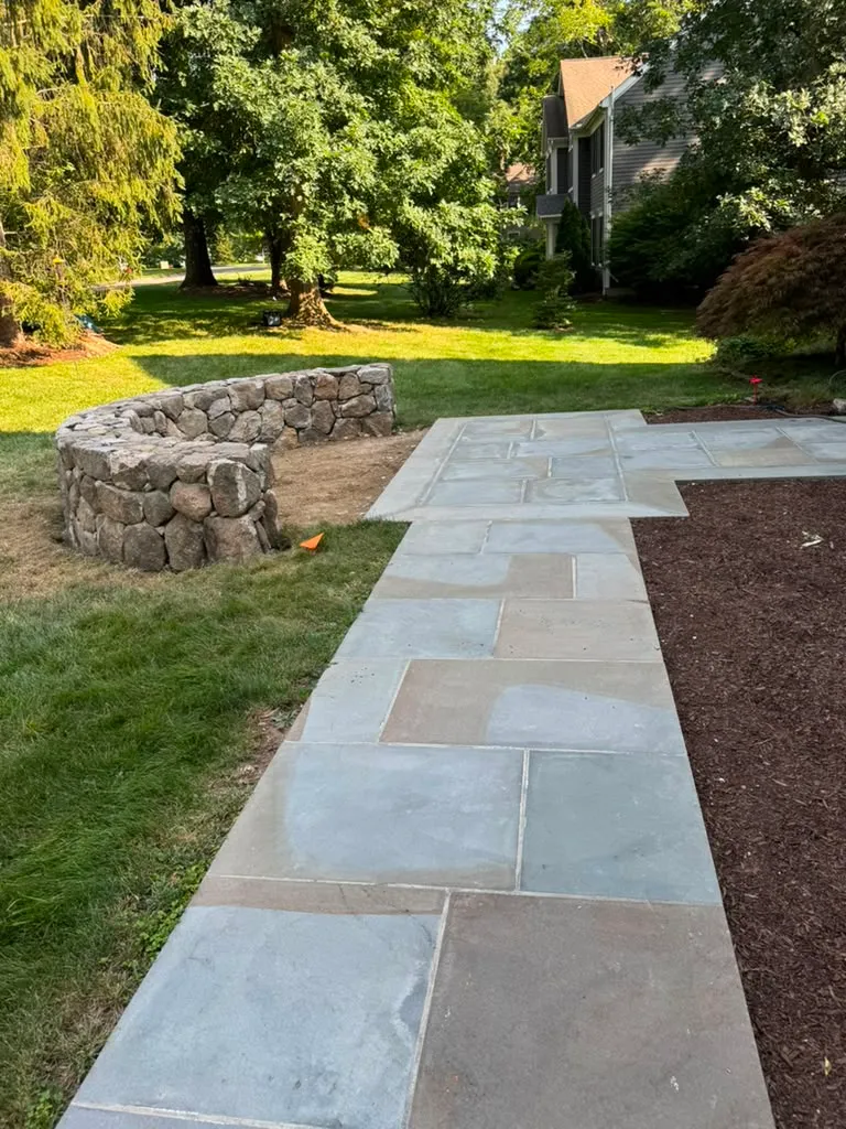 Natural stone retaining wall and stone patio in a Connecticut backyard