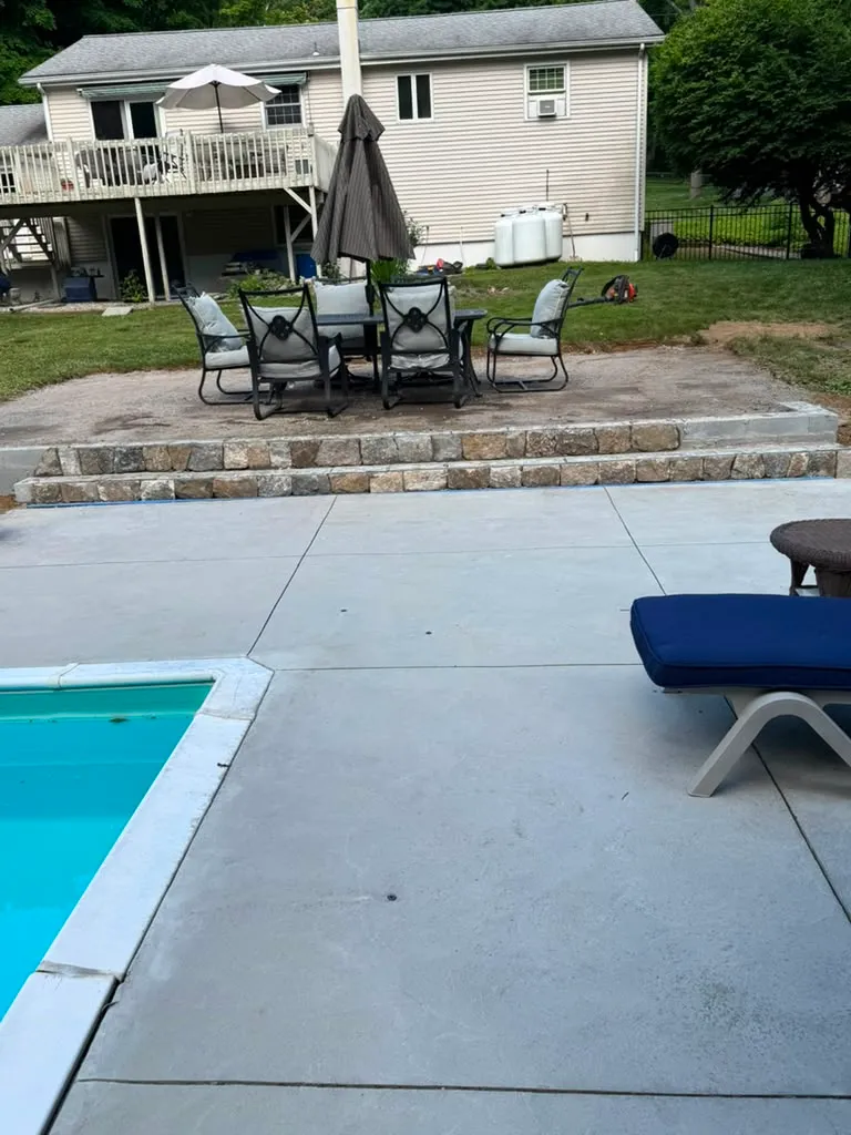 Poured concrete pool deck with natural stone steps in Connecticut